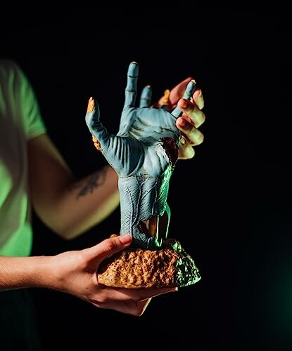 Person holding a zombie hand sculpture